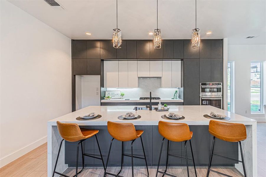 Kitchen featuring modern cabinets, light wood finished floors, a kitchen breakfast bar, light stone counters, and recessed lighting Kitchen featuring modern cabinets, light wood finished floors, a kitchen breakfast bar, light stone counters, and recessed lighting