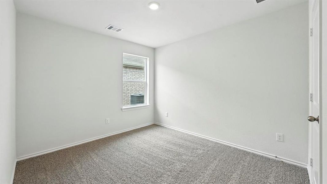 Neutral tone wall finishes, gray carpet flooring, white trim, and a single window with exterior brick siding visible Neutral tone wall finishes, gray carpet flooring, white trim, and a single window with exterior brick siding visible