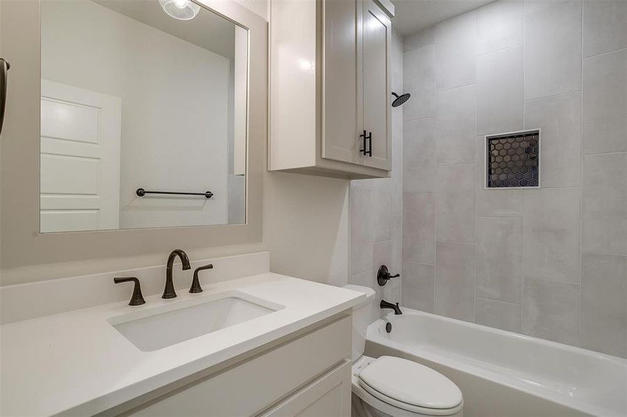 Full bathroom with toilet, tiled shower / bath, and vanity