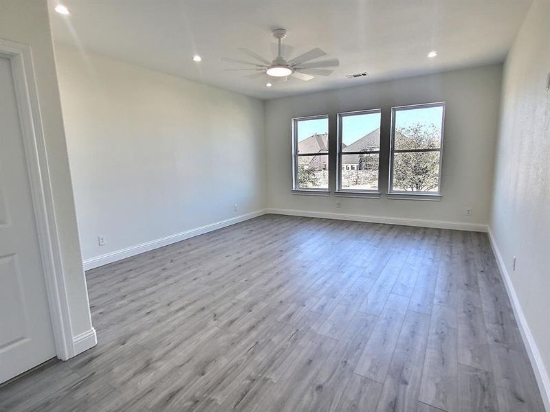 Huge bedroom with light wood-type flooring and ceiling fan and attached bathroom