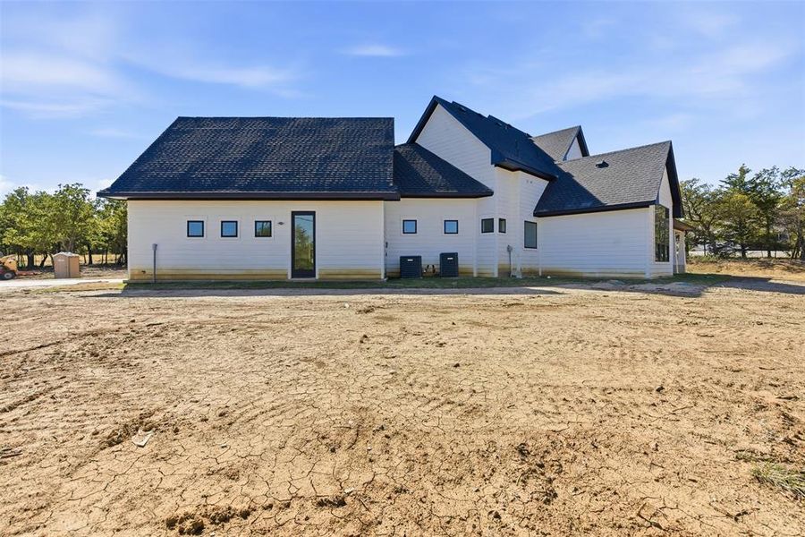 Back of house featuring a shingled roof Back of house featuring a shingled roof