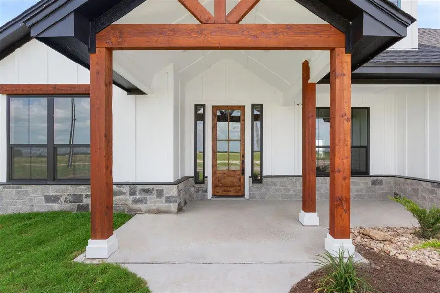 A welcoming entry features a solid wooden door, large windows, and robust wooden beams.