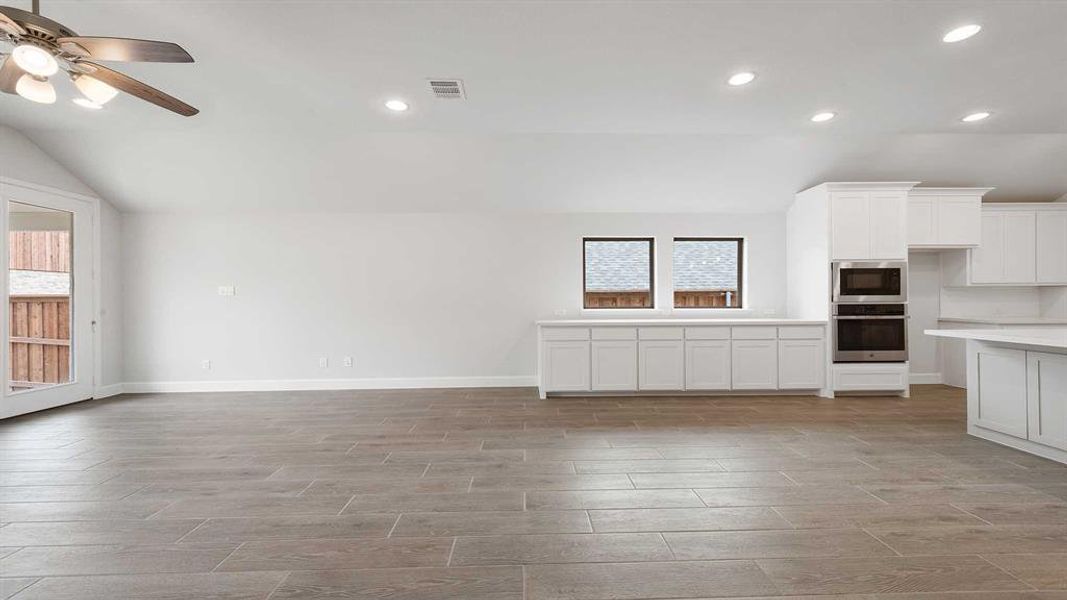 Unfurnished living room with light wood-type flooring, lofted ceiling, and ceiling fan