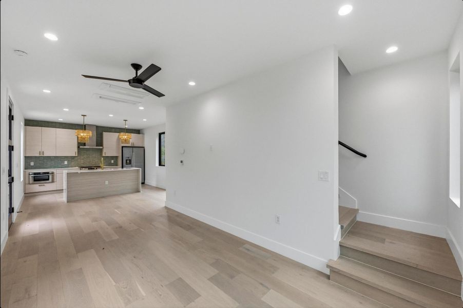Unfurnished living room with light wood-type flooring, a ceiling fan, recessed lighting, and stairway Unfurnished living room with light wood-type flooring, a ceiling fan, recessed lighting, and stairway