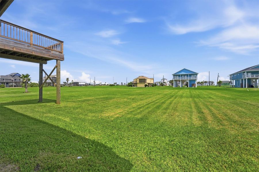 Expansive grassy lot with stilted homes and a wooden deck, perfect for enjoying serene coastal views. Expansive grassy lot with stilted homes and a wooden deck, perfect for enjoying serene coastal views.