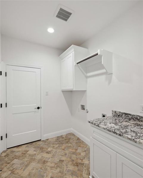 Clothes washing area with cabinets, electric dryer hookup, and washer hookup