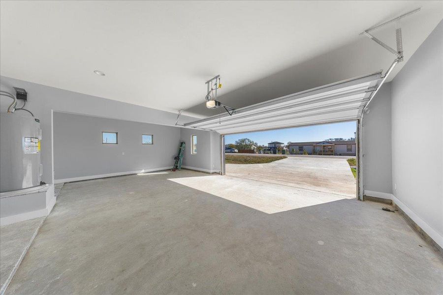 Garage featuring electric water heater and baseboards Garage featuring electric water heater and baseboards