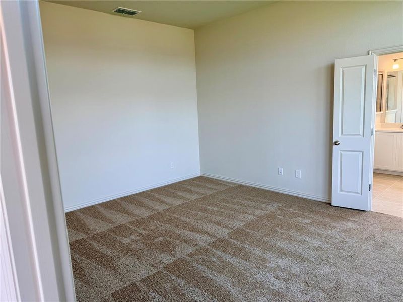 Spacious room featuring neutral carpeting, light-toned walls, and white baseboards