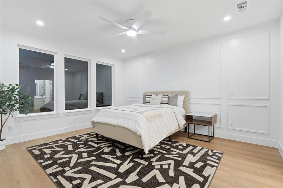 Spacious room featuring three large windows, wood-finish flooring, and recessed lighting Spacious room featuring three large windows, wood-finish flooring, and recessed lighting