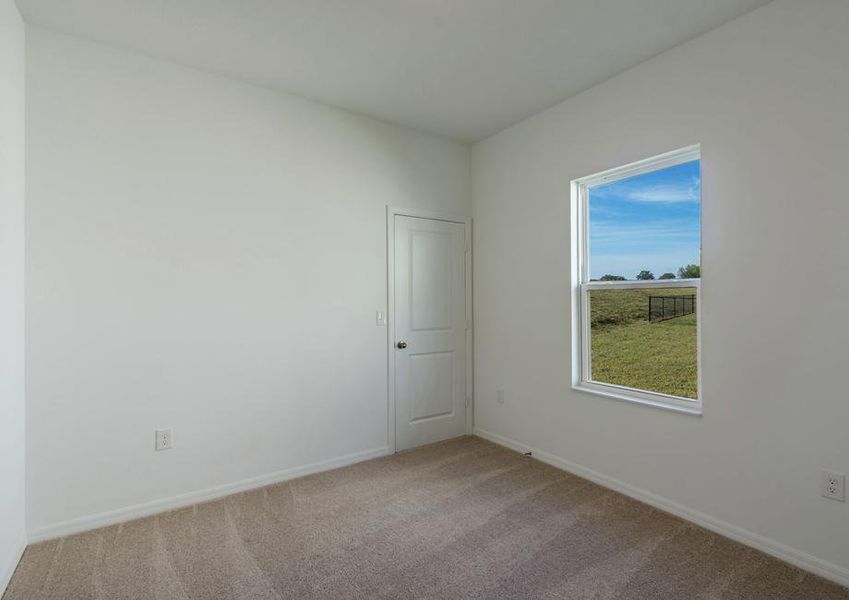 Spare bedroom featuring a large, walk-in closet and a window that lets in plenty of natural light