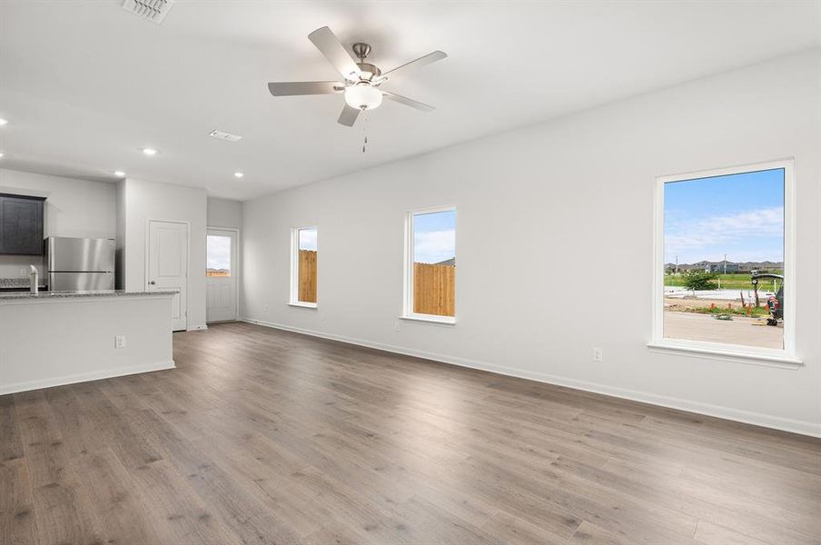 Unfurnished living room with dark wood-type flooring, plenty of natural light, a ceiling fan, and recessed lighting Unfurnished living room with dark wood-type flooring, plenty of natural light, a ceiling fan, and recessed lighting