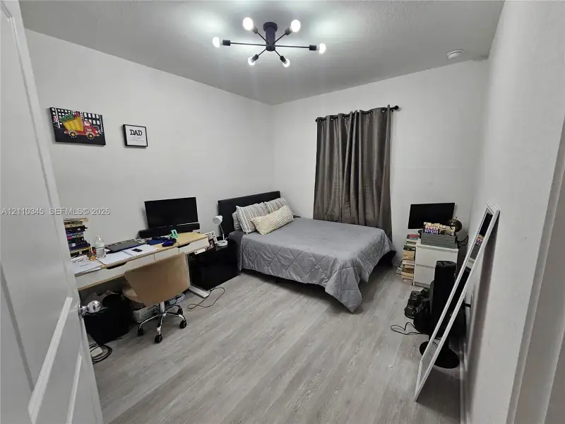Wood-finish flooring, matte black multi-arm sputnik-style ceiling light fixture, and neutral wall tones