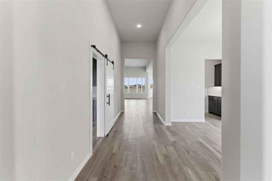 Hall with a barn door, light wood-style floors, and recessed lighting