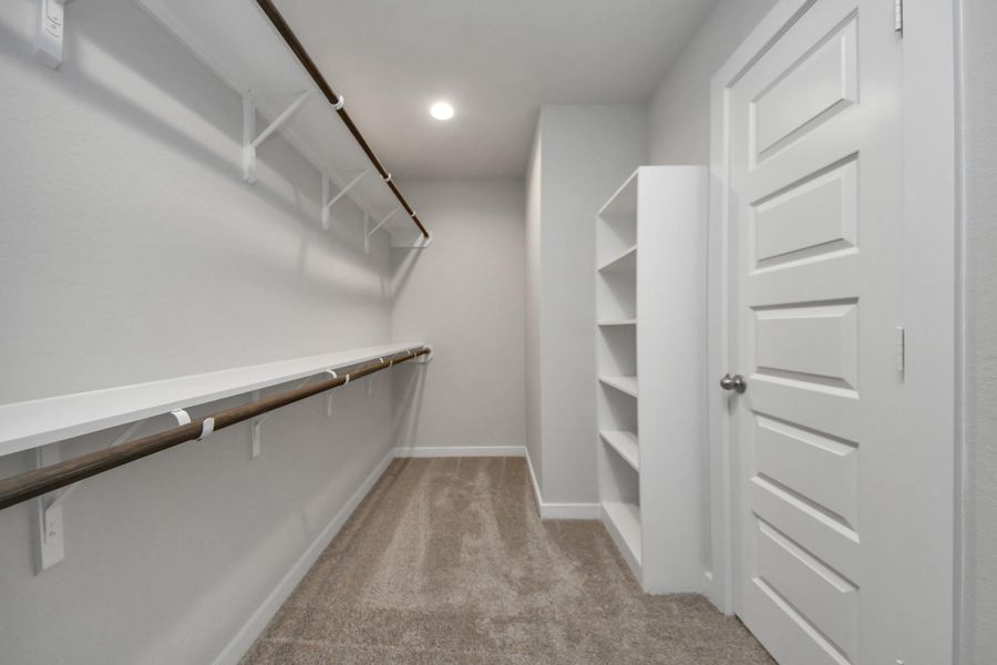 Walk-in closet that epitomizes luxury and practicality. This generously sizedspace features built-in shelving, offering abundant room for impeccableorganization. High ceilings and recessed lighting create a bright andwelcoming ambiance. Sample photo of completed home with similar floor plan. Actual colors and selections may vary.