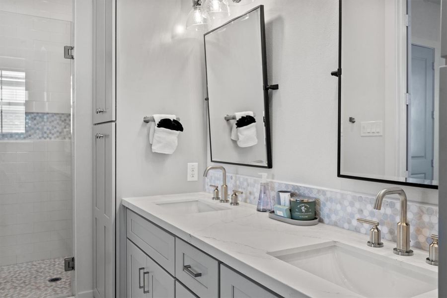 The oversized walk-in shower showcases stunning floor-to-ceiling custom tile work, adding both luxury and a touch of coastal charm.