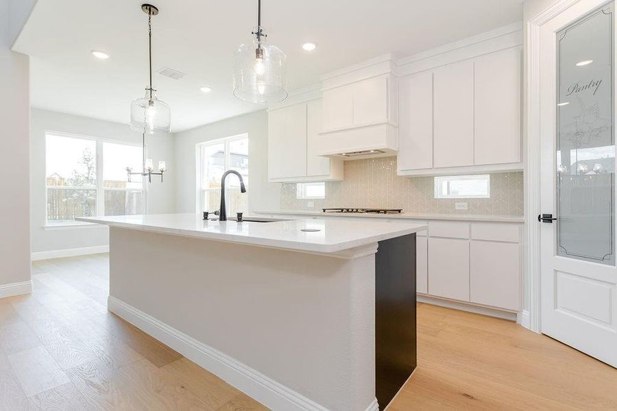 Kitchen featuring light hardwood / wood-style flooring, tasteful backsplash, white cabinets, pendant lighting, and sink