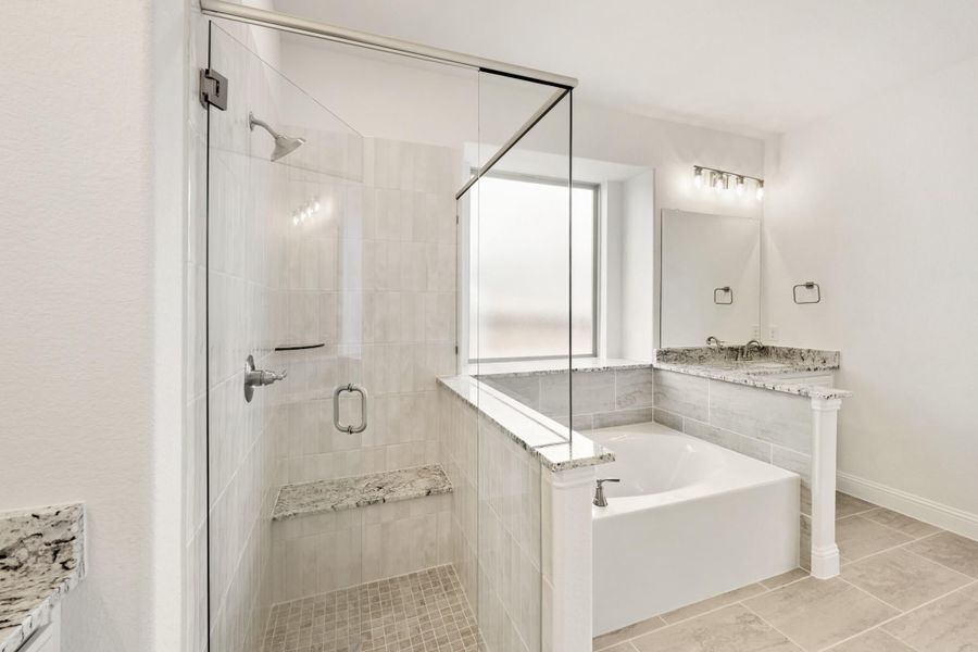 Master bathroom with glass walk-in shower, soaking tub, granite countertop vanity, and light tile floors Master bathroom with glass walk-in shower, soaking tub, granite countertop vanity, and light tile floors
