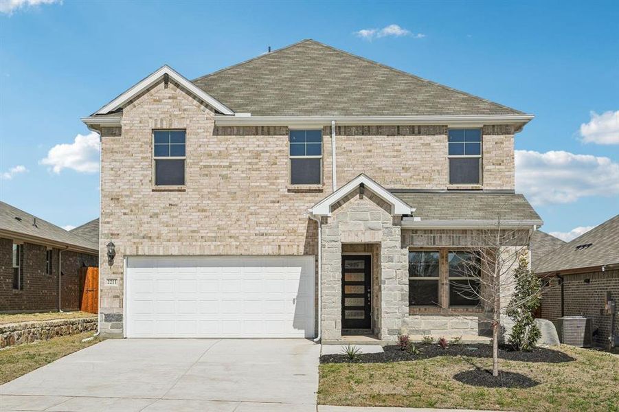 View of front facade with concrete driveway, an attached garage, a shingled roof, stone siding, and brick siding View of front facade with concrete driveway, an attached garage, a shingled roof, stone siding, and brick siding