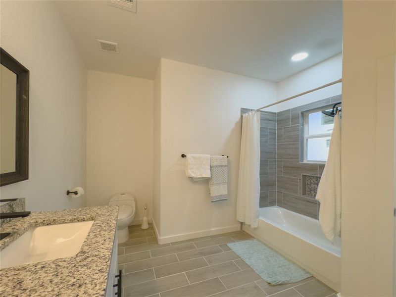 Full bathroom with shower / bathtub combination with curtain, tile flooring, vanity, and toilet