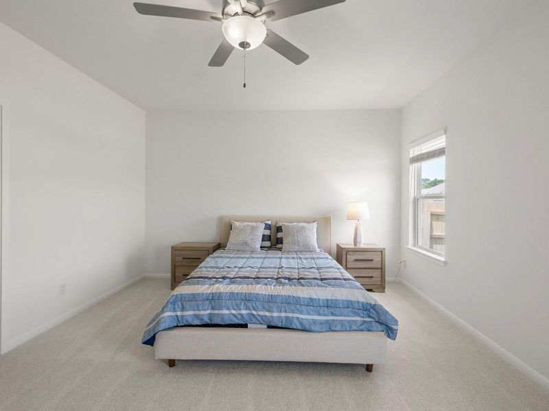 A well-lit bedroom provides comfortable living space with clean, soft carpeting.
