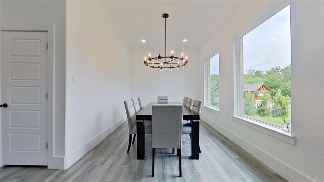 Formal dining area featuring wood-finish flooring and a contemporary chandelier Formal dining area featuring wood-finish flooring and a contemporary chandelier