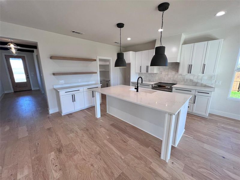 Large serving island with hanging pendent lights and undermount sink.