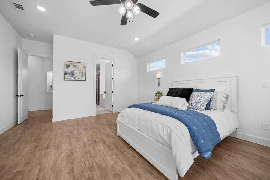 Bedroom featuring light wood-type flooring, recessed lighting, a ceiling fan, ensuite bath, and vaulted ceiling