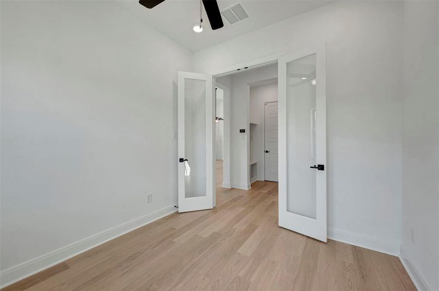 Unfurnished bedroom featuring light wood-style floors, a ceiling fan, and french doors Unfurnished bedroom featuring light wood-style floors, a ceiling fan, and french doors