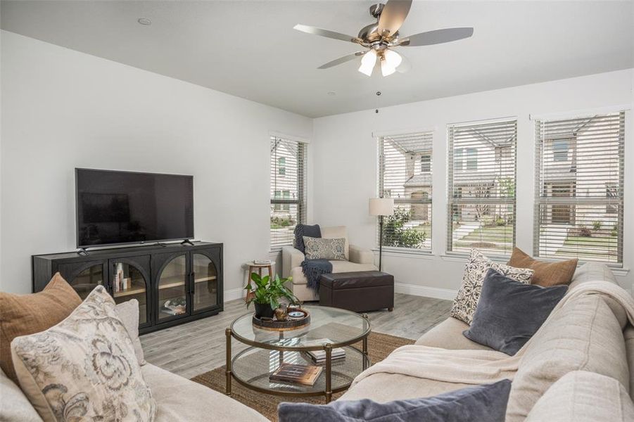 Living area showcases a wall of windows, ceiling fan, and flexible seating layout for comfort and functionality.