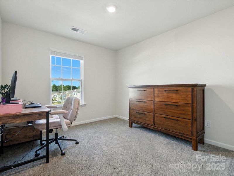 Versatile upper-level room perfect for home office, playroom, or additional bedroom. Carpet flooring, recessed lighting, and large window provide comfortable space for work or relaxation.
