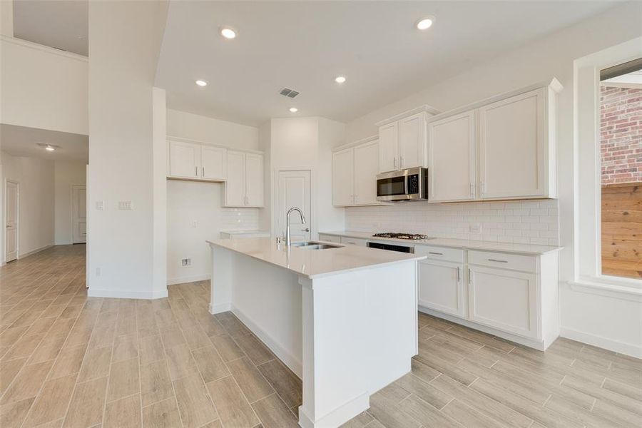 Kitchen with white cabinetry, sink, an island with sink, and light hardwood / wood-style floors