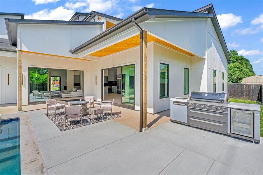 Rear view of property featuring beverage cooler, an outdoor living space, exterior kitchen, and a patio area