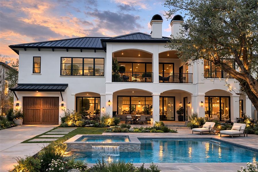Back of property at dusk featuring a standing seam roof, stucco siding, a balcony, a patio, and an attached garage