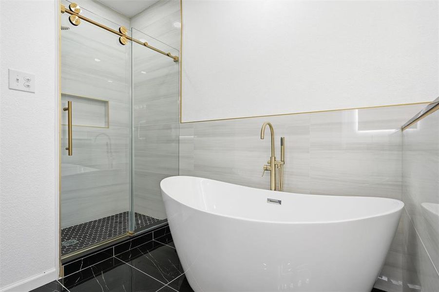 Bathroom featuring a freestanding tub, a stall shower, and tile walls Bathroom featuring a freestanding tub, a stall shower, and tile walls