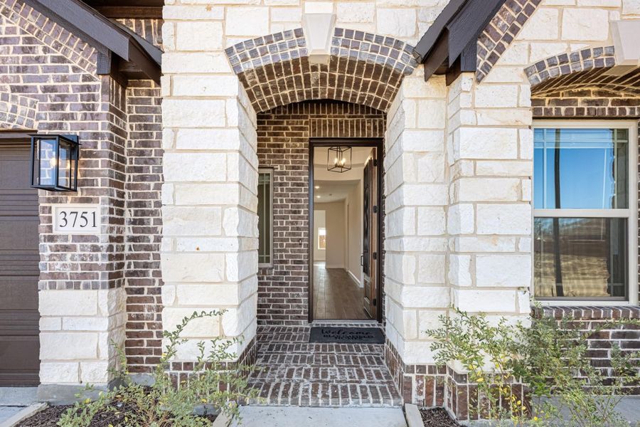 Home entrance with stone and brick arched entryway, black front door, and pendant light fixture at address 3751. Home entrance with stone and brick arched entryway, black front door, and pendant light fixture at address 3751.