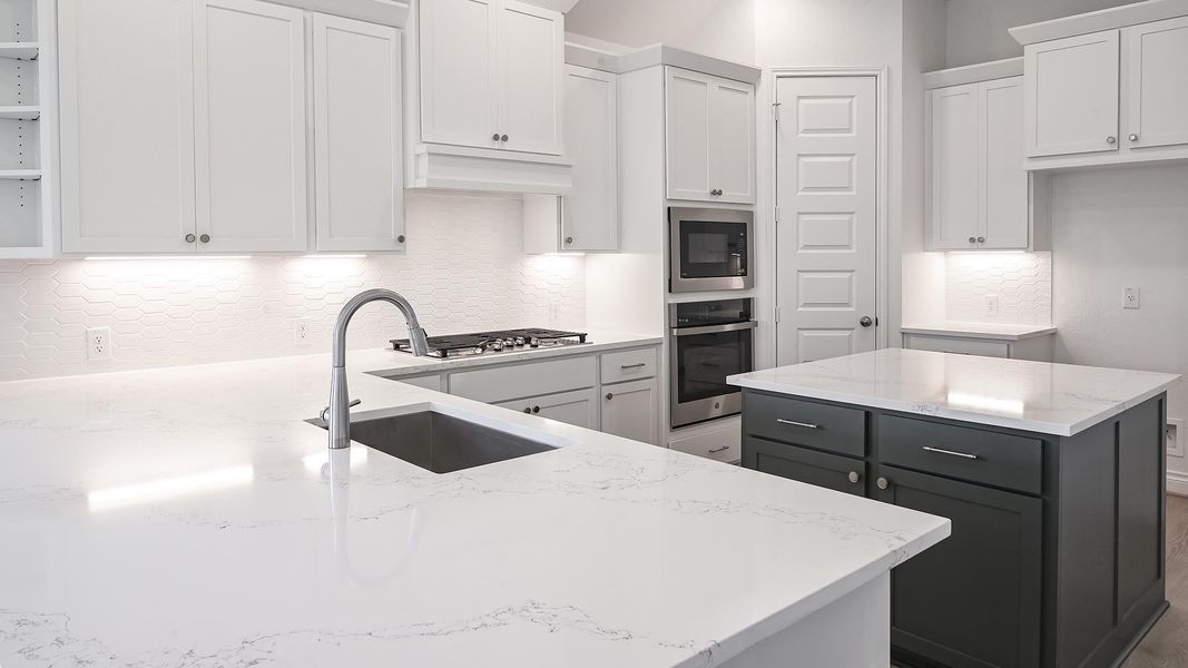 Kitchen with decorative backsplash, white cabinets, a kitchen island, appliances with stainless steel finishes, and light stone counters Kitchen with decorative backsplash, white cabinets, a kitchen island, appliances with stainless steel finishes, and light stone counters