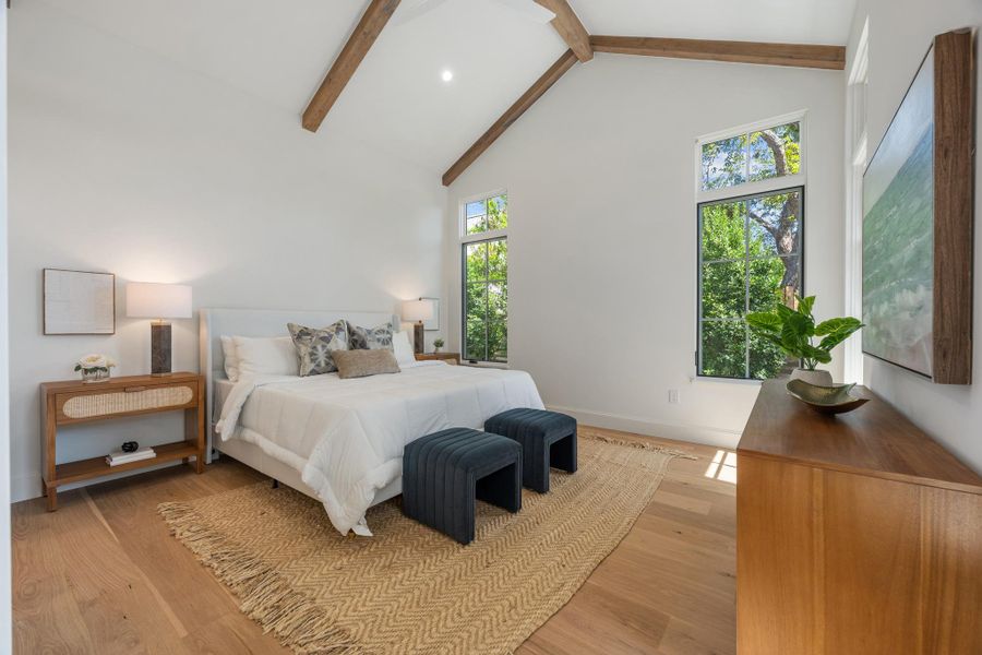 Exposed wood beams and rich hardwood flooring frame this airy bedroom space.