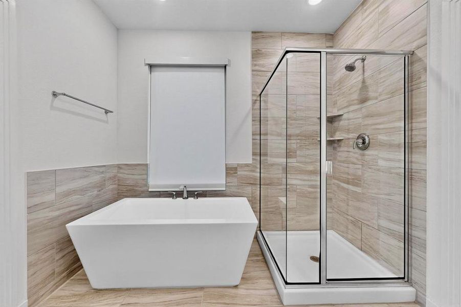 Full bath featuring tile walls, a stall shower, a freestanding bath, and wainscoting Full bath featuring tile walls, a stall shower, a freestanding bath, and wainscoting