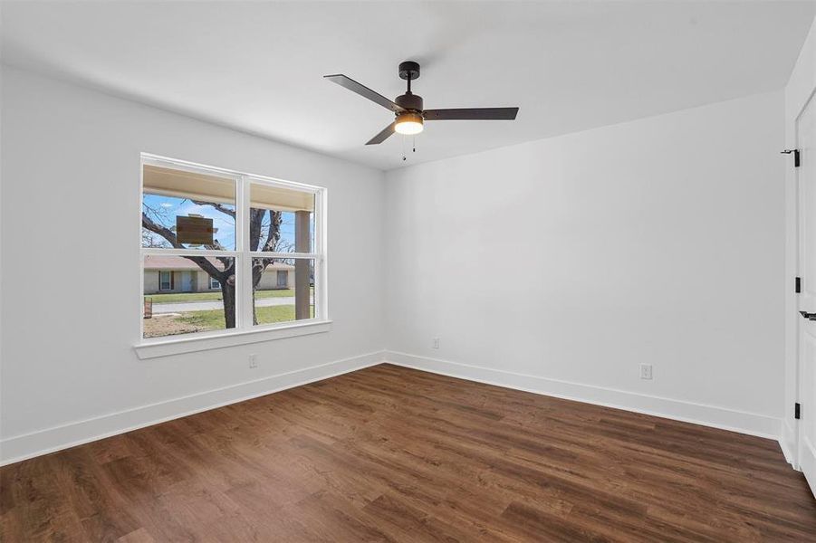 Spare room featuring ceiling fan, baseboards, and dark wood-style flooring