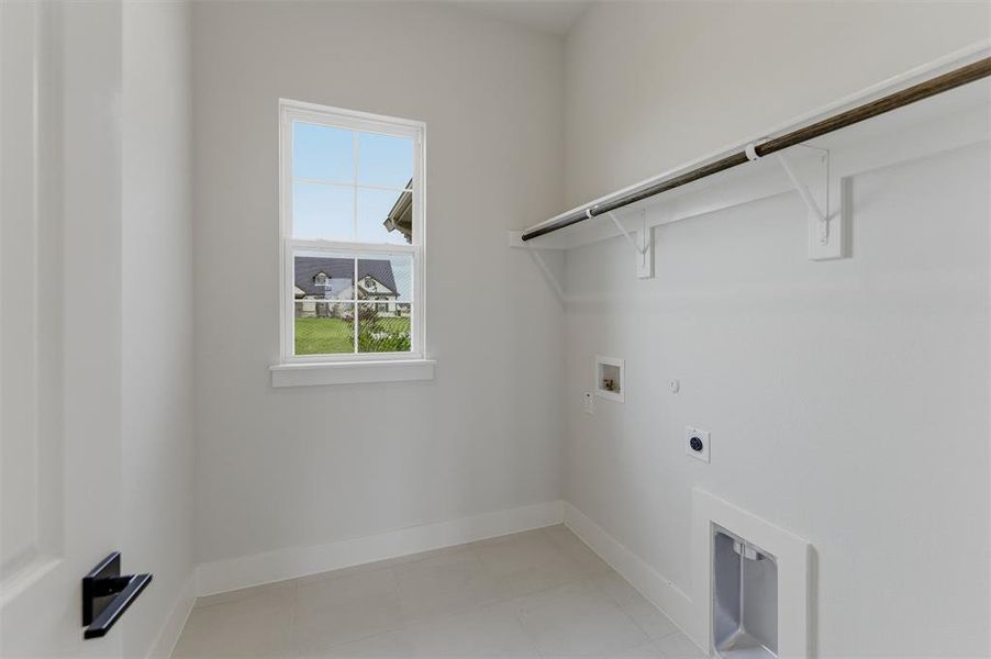 Utility room with light gray walls, a window, a single clothing rod, and connections for laundry appliances