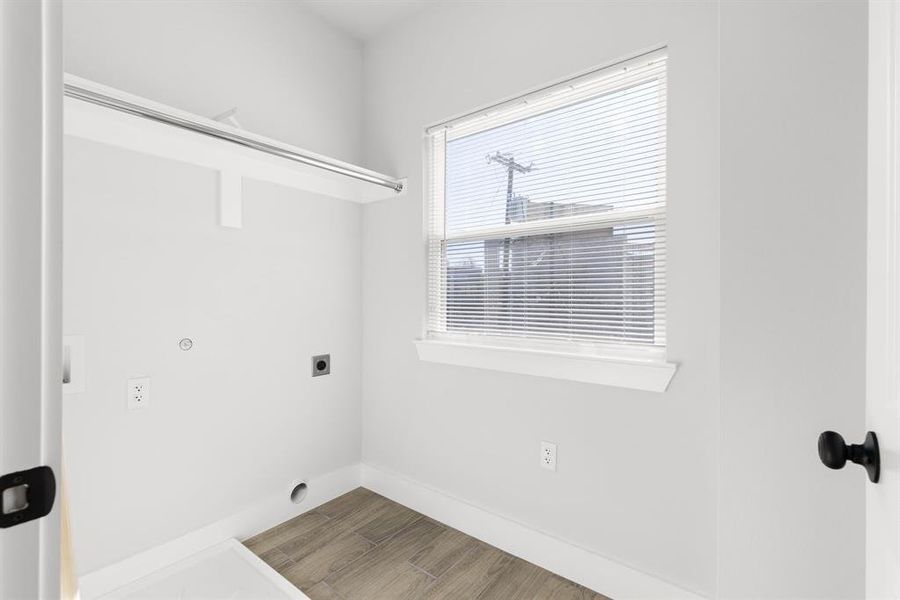 Clothes washing area with laundry area, baseboards, hookup for an electric dryer, and wood finished floors