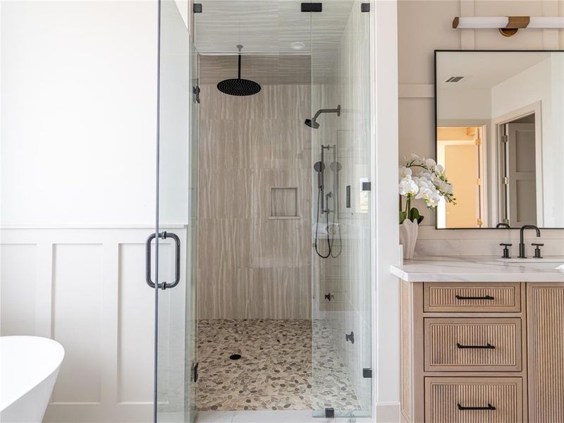 Bathroom featuring a stall shower, vanity, a freestanding tub, a wainscoted wall, and a decorative wall