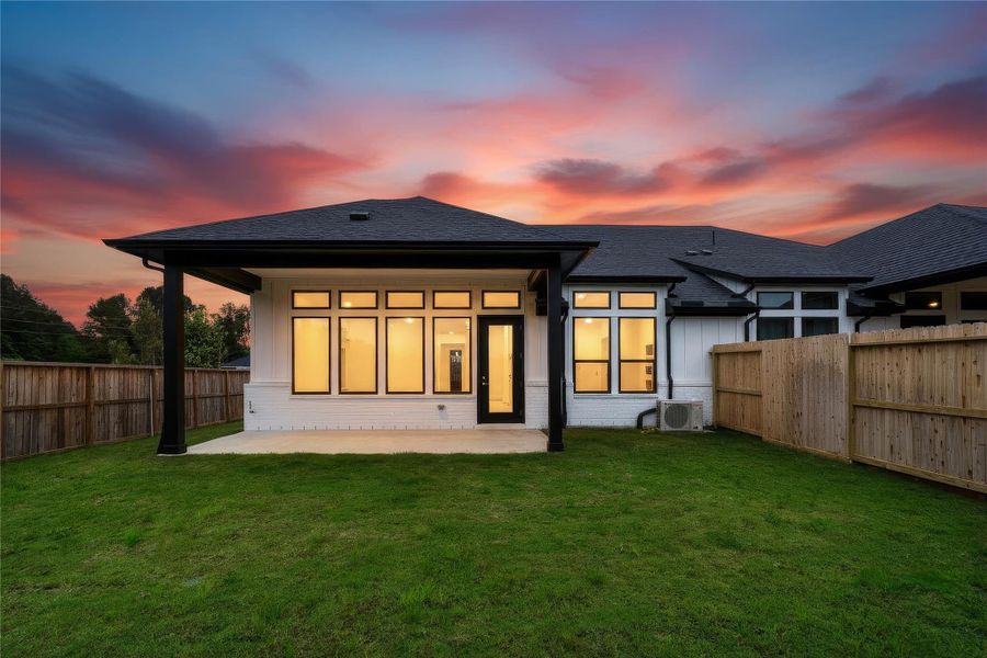Step outside to a private backyard oasis, perfect for relaxing or outdoor entertaining. The yard offers a blend of privacy with a tall wood fence and an open feel provided by a black metal fence, overlooking the surrounding community and mature trees.