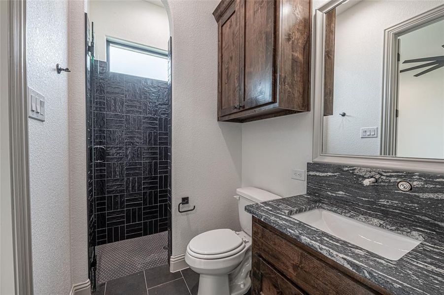 Bathroom featuring vanity, a shower stall, and dark tile patterned flooring Bathroom featuring vanity, a shower stall, and dark tile patterned flooring