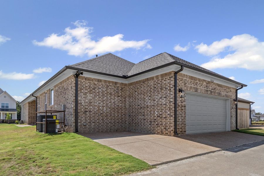View of property exterior featuring brick siding, an attached garage, roof with shingles, concrete driveway, and a lawn View of property exterior featuring brick siding, an attached garage, roof with shingles, concrete driveway, and a lawn