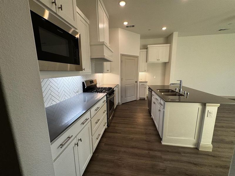 Kitchen with backsplash, sink, dark hardwood / wood-style floors, white cabinetry, and stainless steel appliances