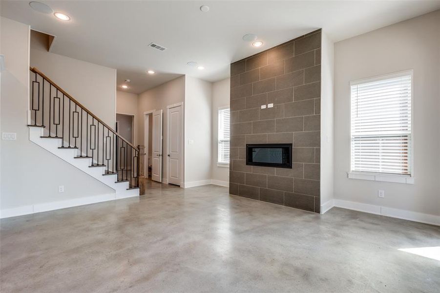 Unfurnished living room with tile walls, concrete flooring, and a fireplace