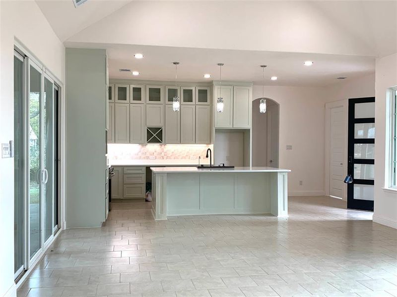 Kitchen with healthy amount of natural light, a kitchen island with sink, recessed lighting, decorative backsplash, and glass insert cabinets Kitchen with healthy amount of natural light, a kitchen island with sink, recessed lighting, decorative backsplash, and glass insert cabinets