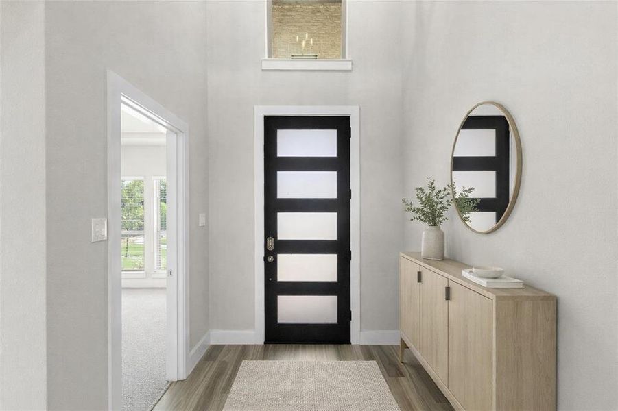 Two-story entryway featuring a modern black front door with frosted glass panels, wood-finish flooring, and a transom window Two-story entryway featuring a modern black front door with frosted glass panels, wood-finish flooring, and a transom window