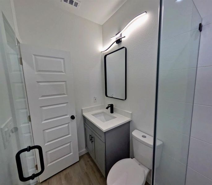Bathroom featuring light wood finished floors, vanity, and a stall shower Bathroom featuring light wood finished floors, vanity, and a stall shower